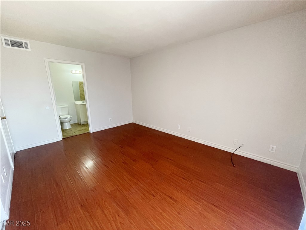5447 Retablo Avenue, Unit 4 Las Vegas, NV 89103 - Photo 13 of 16 Unfurnished bedroom featuring wood finished floors and ensuite bath