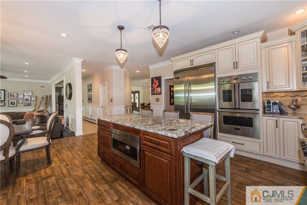 16 Ron's Edge Road Springfield, NJ 07081 - Photo 9 of 25 a kitchen with stainless steel appliances granite countertop a stove top oven a refrigerator a sink and chairs