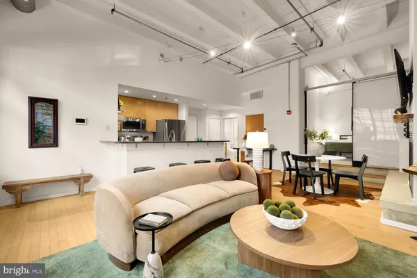 a living room with furniture kitchen view and a wooden floor