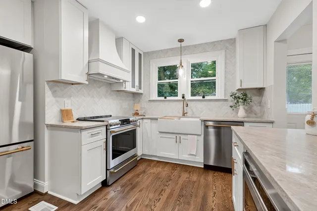 a kitchen with stainless steel appliances white cabinets a sink and a stove