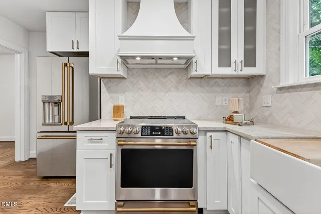 a kitchen with stainless steel appliances granite countertop a stove a sink and a white cabinets