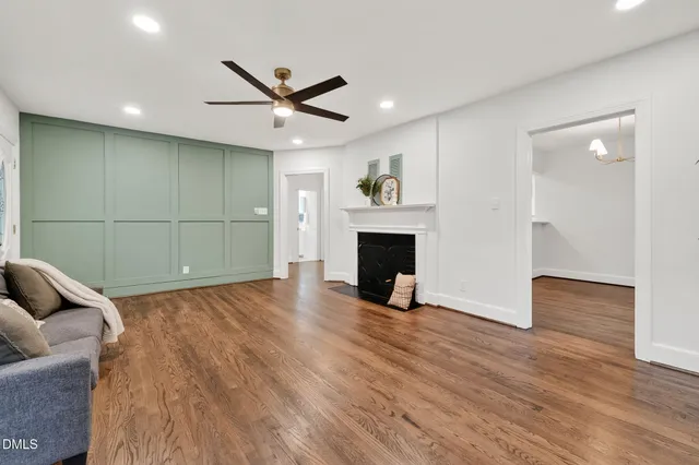 a view of empty room with wooden floor and fan