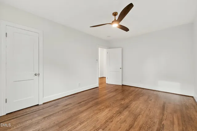 an empty room with wooden floor cabinet and windows