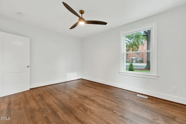 a view of an empty room with wooden floor and a window