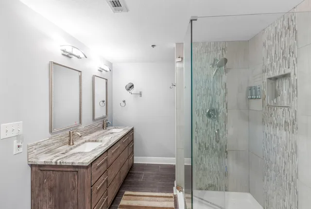 a bathroom with a granite countertop sink a mirror and shower