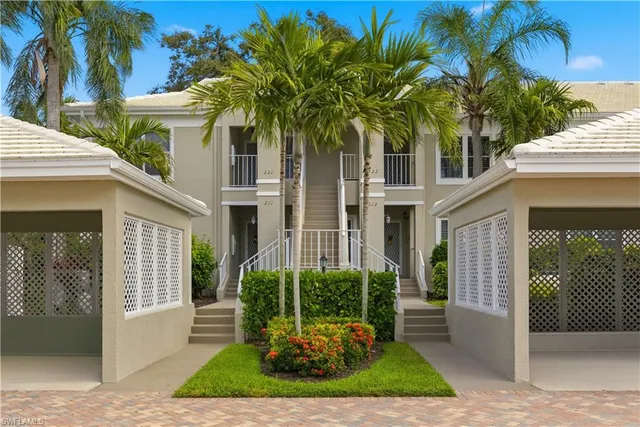 a view of a white house next to a yard with palm trees