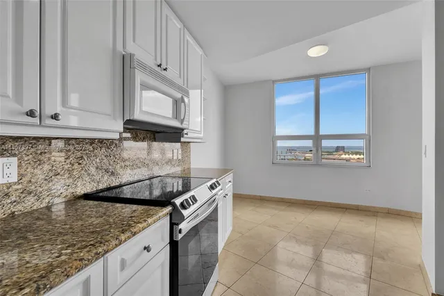 a kitchen with granite countertop a sink a stove and cabinets