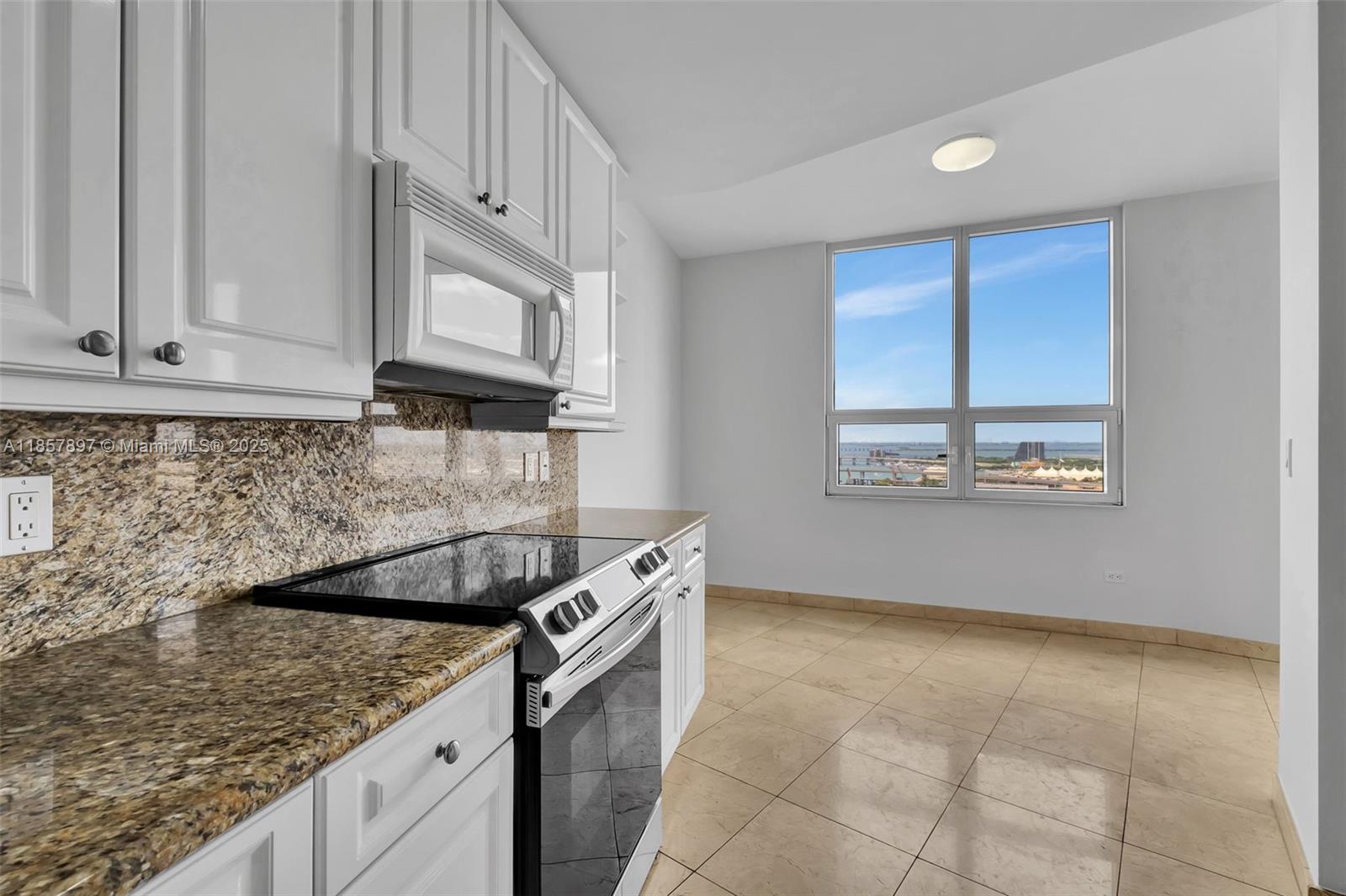 848 Brickell Key Drive, Unit 2602 Miami, FL 33131 - Photo 14 of 40 a kitchen with granite countertop a sink a stove and cabinets