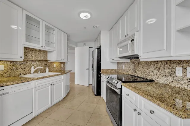 a kitchen with granite countertop a sink stove and cabinets