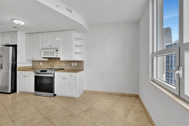 a kitchen with granite countertop white cabinets and stainless steel appliances