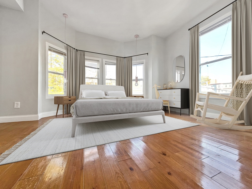 26 Arcadia Street, Unit 2L Boston, MA 02122 - Photo 2 of 9 a spacious bedroom with a bed couch and a large window with wooden floor
