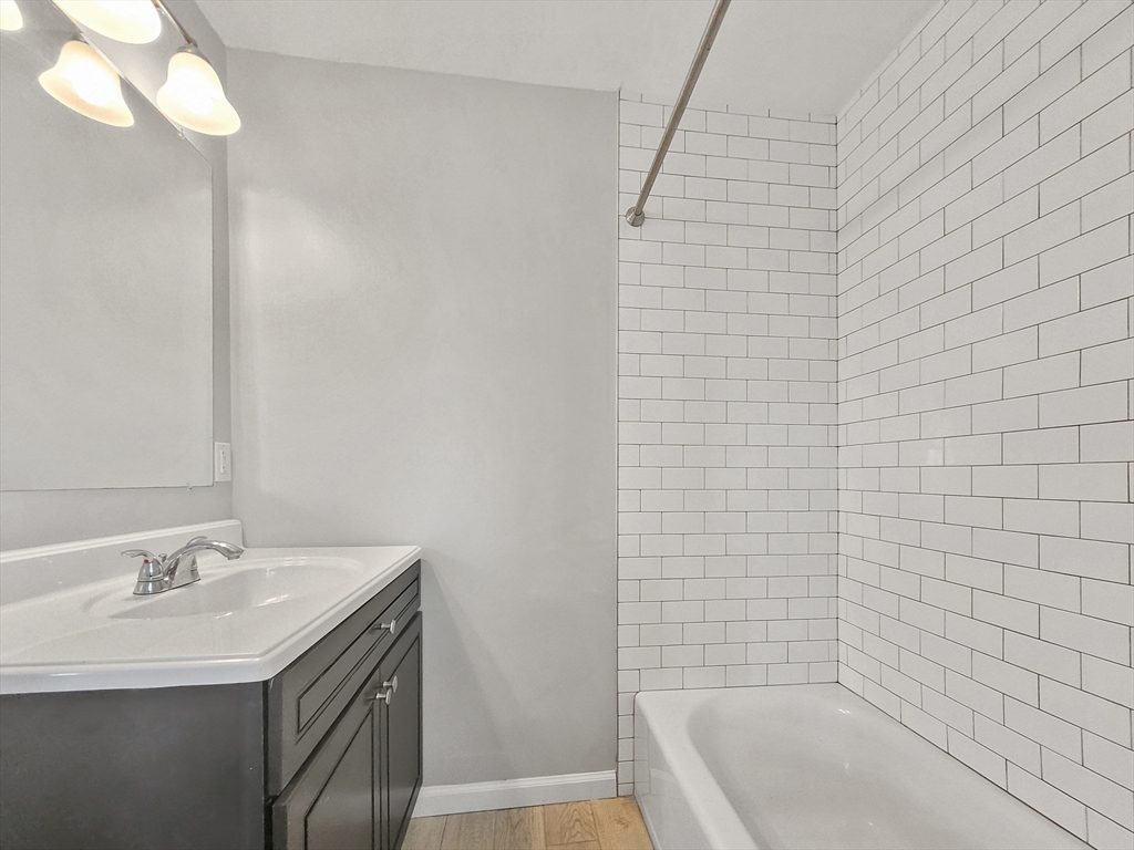 26 Arcadia Street, Unit 2L Boston, MA 02122 - Photo 6 of 9 a bathroom with a granite countertop sink a toilet and bathtub