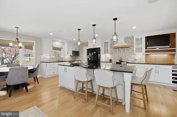 a kitchen with kitchen island granite countertop a dining table chairs and white cabinets