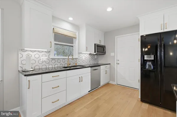 a kitchen with granite countertop white cabinets and stainless steel appliances