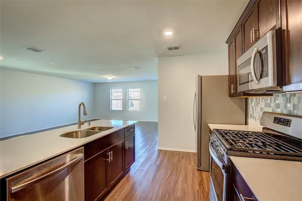 a kitchen with a sink stove top oven and wooden floor