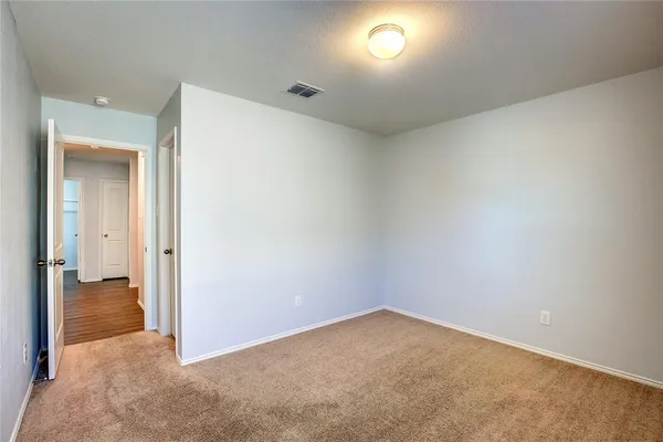 an empty room with wooden floor and a hallway