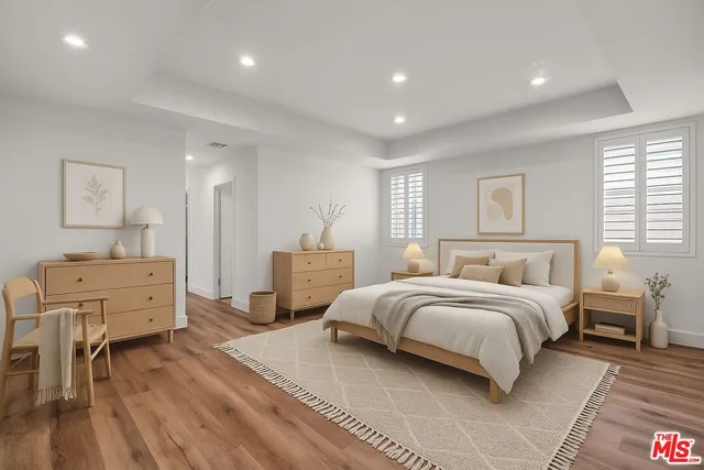a spacious bedroom with a bed a table and a dresser