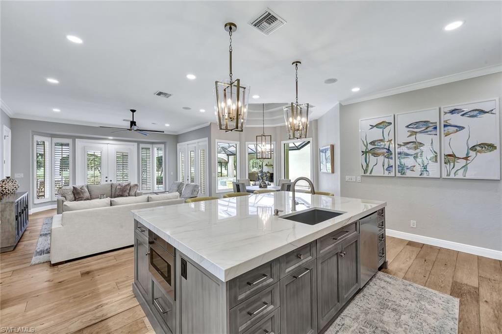 4624 Pond Apple Drive North Naples, FL 34119 - Photo 12 of 46 a large kitchen with kitchen island a large island a sink and a wooden floor