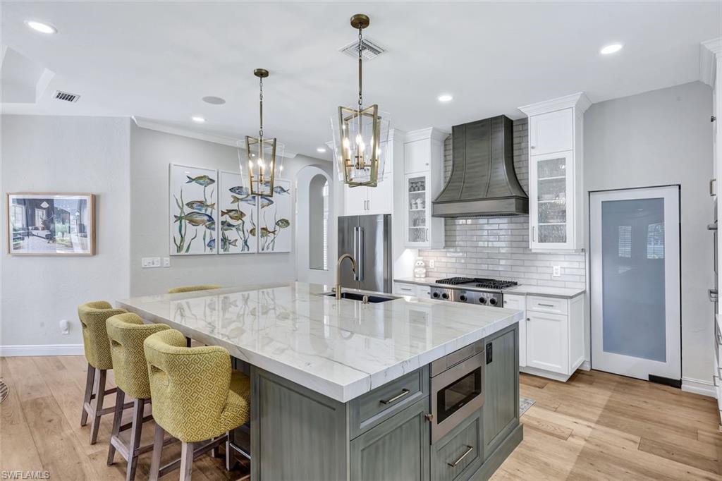 4624 Pond Apple Drive North Naples, FL 34119 - Photo 13 of 46 a kitchen that has a stove a table and chairs in it