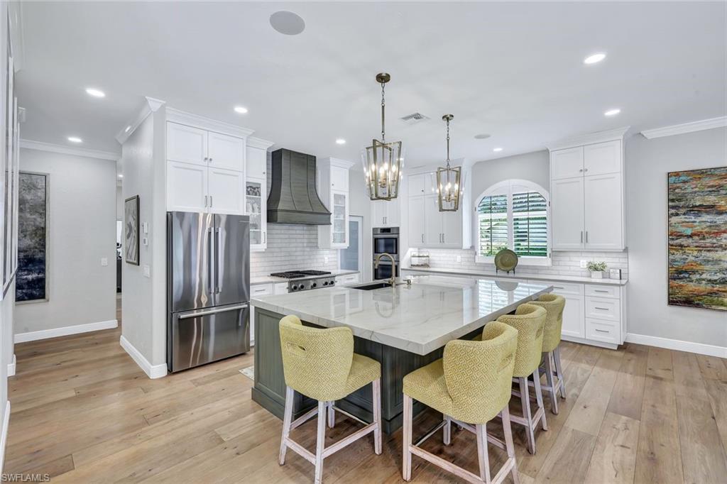 4624 Pond Apple Drive North Naples, FL 34119 - Photo 14 of 46 a kitchen with stainless steel appliances kitchen island granite countertop a dining table chairs and refrigerator