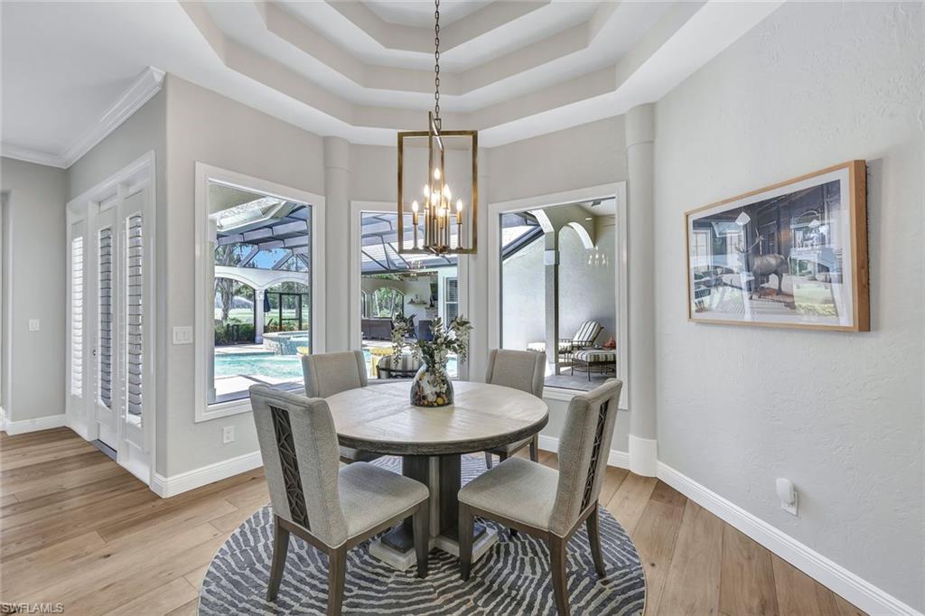 4624 Pond Apple Drive North Naples, FL 34119 - Photo 16 of 46 a dining room with furniture a chandelier and wooden floor