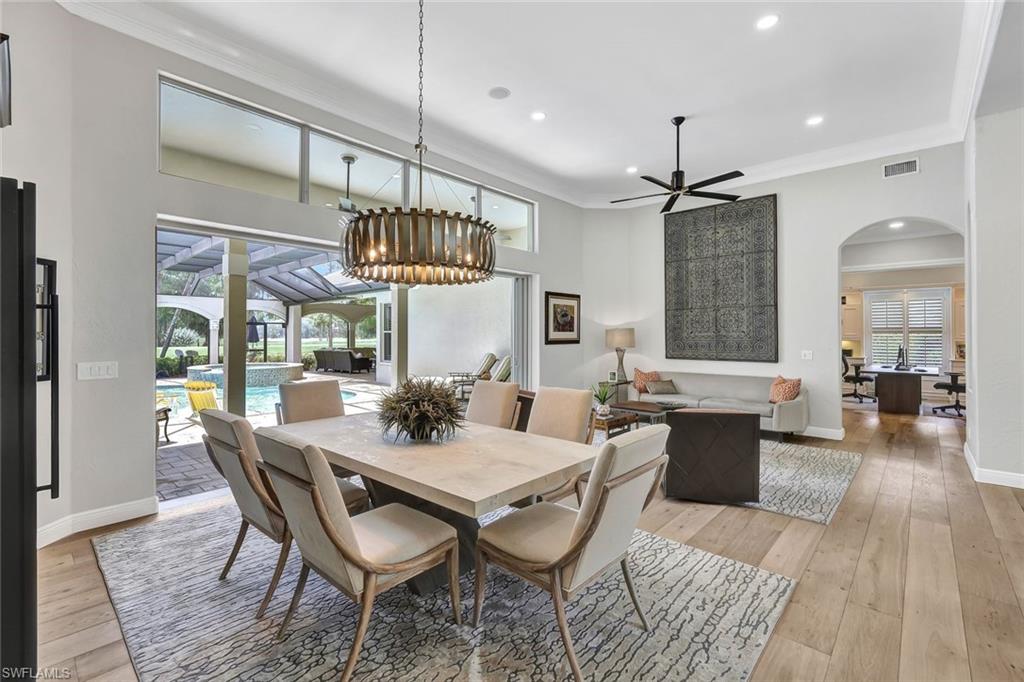 4624 Pond Apple Drive North Naples, FL 34119 - Photo 18 of 46 a dining room with wooden floor a chandelier a wooden table and chairs