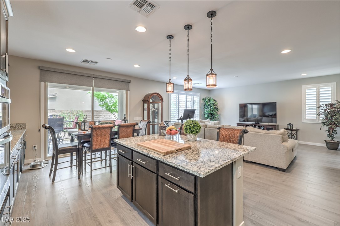2711 Evolutionary Lane Las Vegas, NV 89138 - Photo 14 of 37 Kitchen with light wood-style flooring, baseboards, recessed lighting, light stone countertops, and a kitchen island