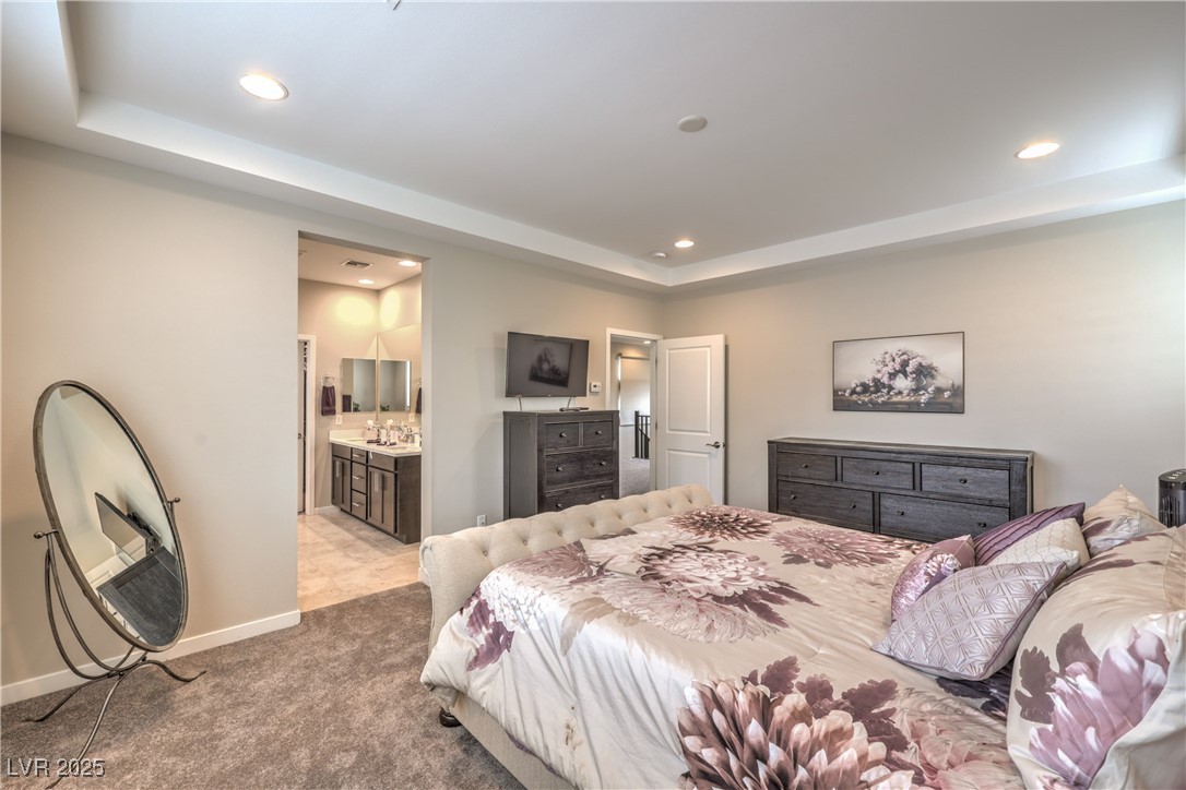2711 Evolutionary Lane Las Vegas, NV 89138 - Photo 23 of 37 Bedroom with a raised ceiling, recessed lighting, light colored carpet, ensuite bath, and baseboards