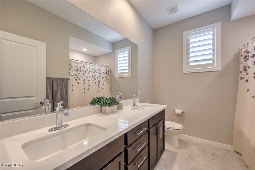 2711 Evolutionary Lane Las Vegas, NV 89138 - Photo 28 of 37 Full bathroom featuring double vanity, baseboards, toilet, and a shower with curtain