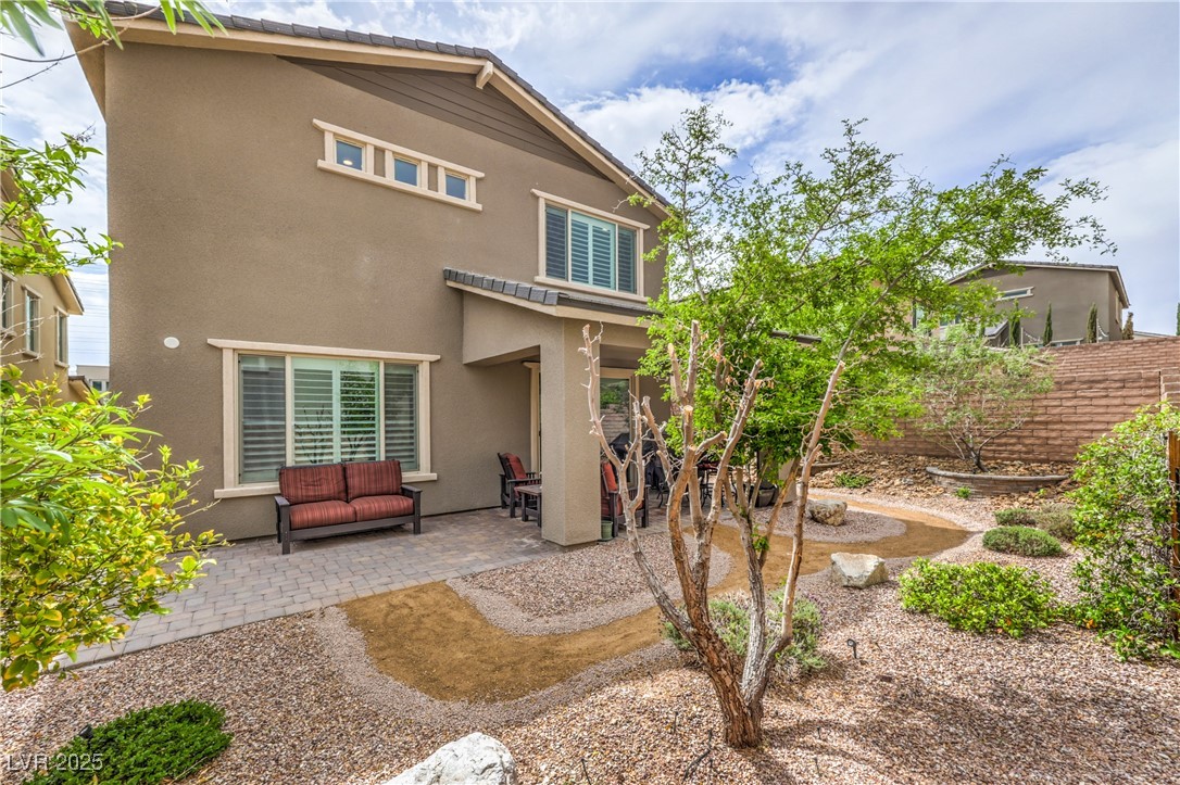 2711 Evolutionary Lane Las Vegas, NV 89138 - Photo 33 of 37 Rear view of house featuring stucco siding, a patio, and outdoor lounge area