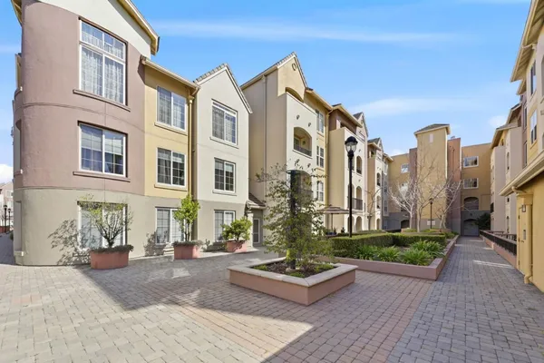 a front view of a multi story residential apartment building with yard and bench