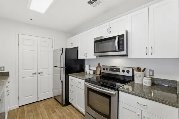 a kitchen with granite countertop white cabinets and stainless steel appliances