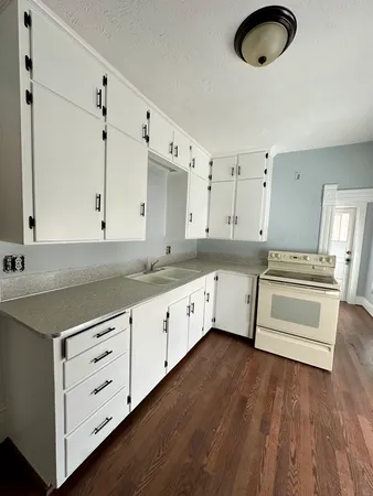 a kitchen with granite countertop a stove cabinets and wooden floor