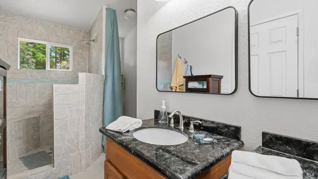 a bathroom with a granite countertop sink and a mirror