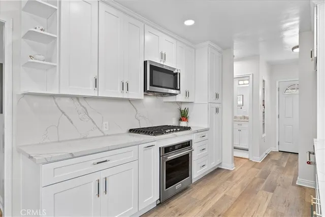 a kitchen with stainless steel appliances granite countertop white cabinets and a stove top oven