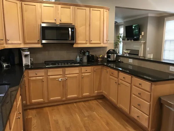 a kitchen with granite countertop white cabinets and black stainless steel appliances