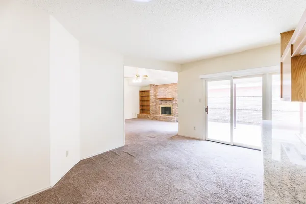 an empty room with windows and chandelier fan