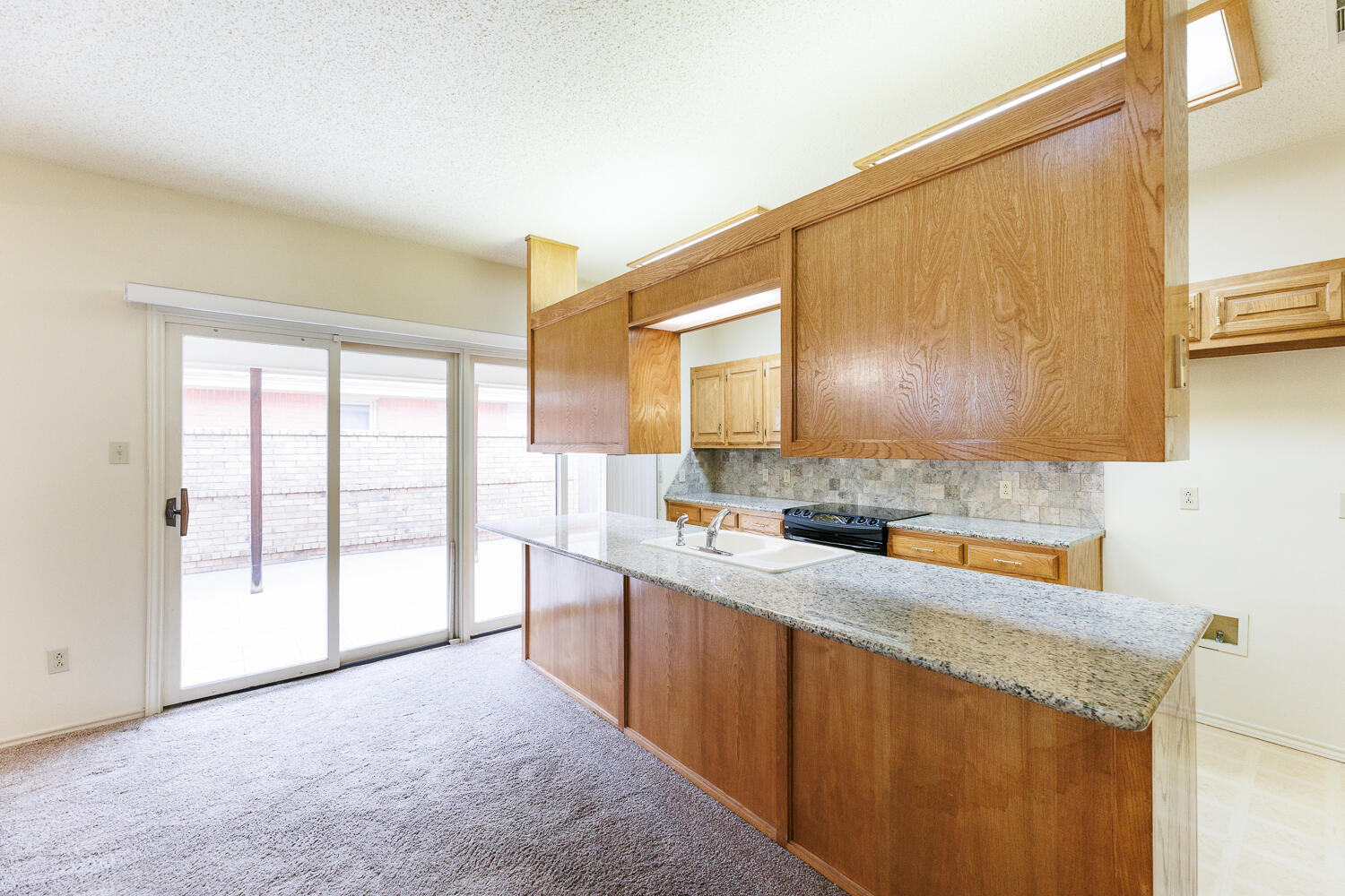7610 Utica Avenue Lubbock, TX 79424 - Photo 15 of 49 a kitchen with a sink a stove cabinets and a wooden floor