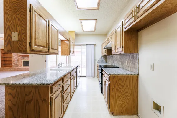 a kitchen with stainless steel appliances granite countertop a sink a stove and a wooden cabinets