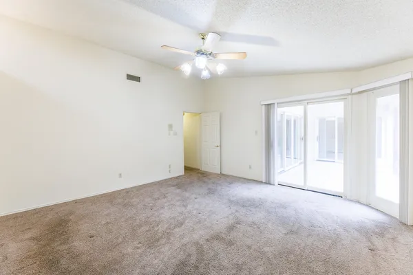 an empty room with fan and windows