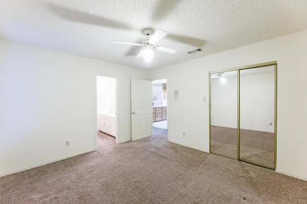 an empty room with closet and a ceiling fan