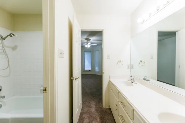 a spacious bathroom with a double vanity sink a mirror and a bathtub