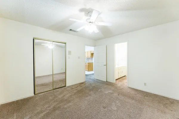 an empty room with closet and a ceiling fan