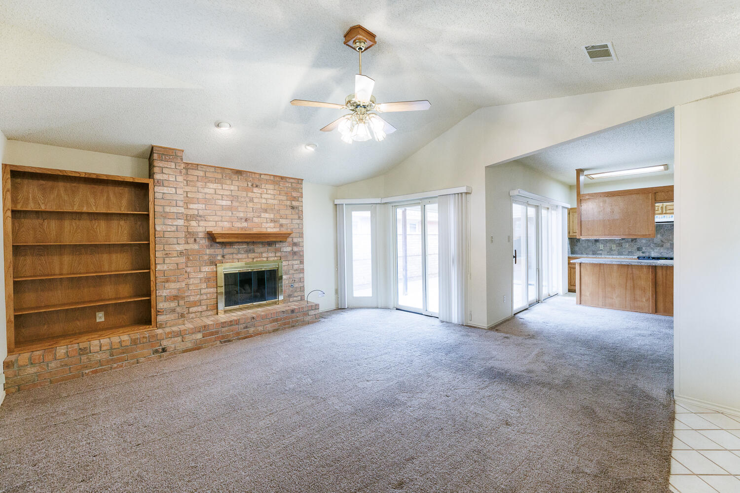 7610 Utica Avenue Lubbock, TX 79424 - Photo 9 of 49 a view of an empty room with a fireplace and a fan