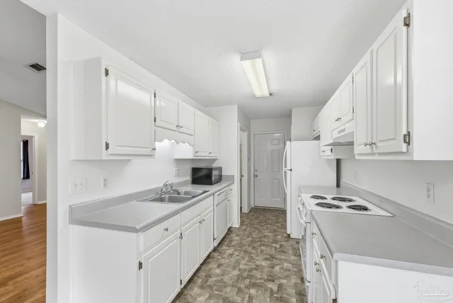 a kitchen with granite countertop a sink stove and refrigerator
