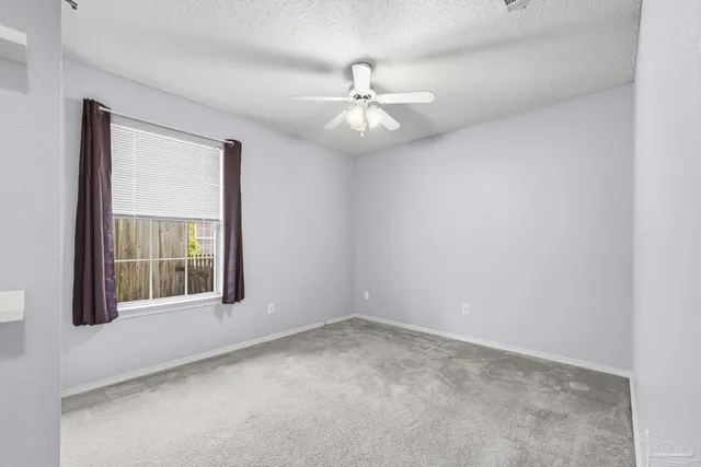 an empty room with windows and fan