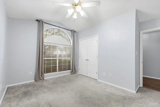 an empty room with windows and ceiling fan