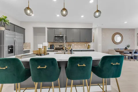 a living room with stainless steel appliances kitchen island granite countertop a dining table chairs and a refrigerator