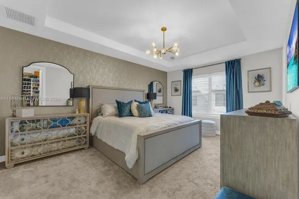 a spacious bedroom with a bed a chandelier and a dresser