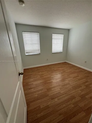 a view of an empty room with closet and wooden floor